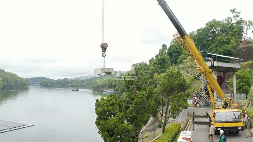 Crane lowering a concrete anchor block for the floating solar mooring system
