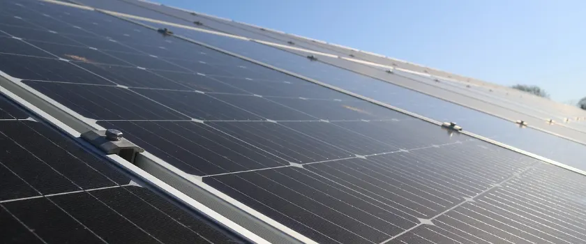 Aluminum mid and end clamps securing framed solar panels in an array under a clear blue sky